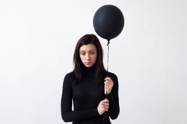 Sad girl holding a black balloon while wearing a black top